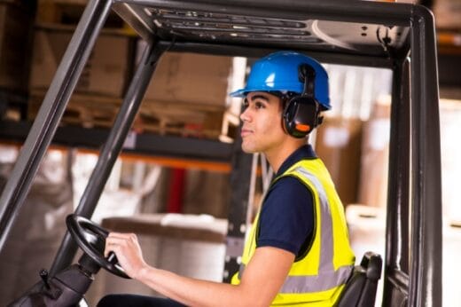 Young worker operating a forklift in a warehouse.